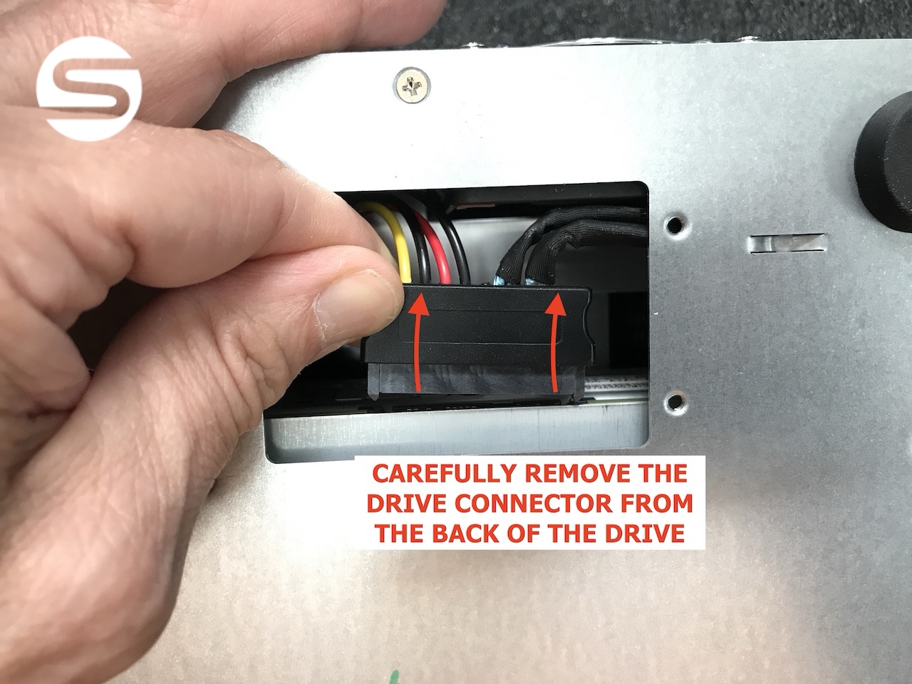 A hand reaching into the inspection panel to carefully unplug the connector from the rear of the LTO drive